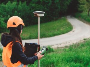 Land surveyor using GPS equipment to collect topographic survey data near a roadway in Fairfax, VA.